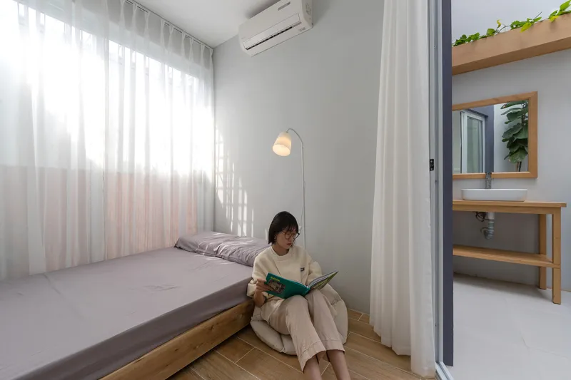 Bedroom with timber platform bed and white curtains diffusing afternoon sunlight