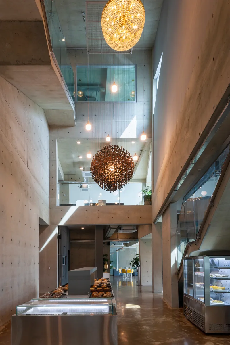 Vertical view through atrium showing stacked concrete floors, glass railings and spherical pendant fixtures