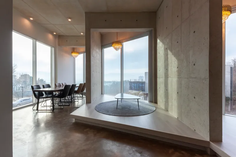 Raised platform seating area with concrete walls and corner windows overlooking winter landscape
