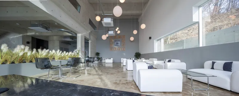Open lounge area with polished concrete floor, white seating, and planters along the glass balustrade