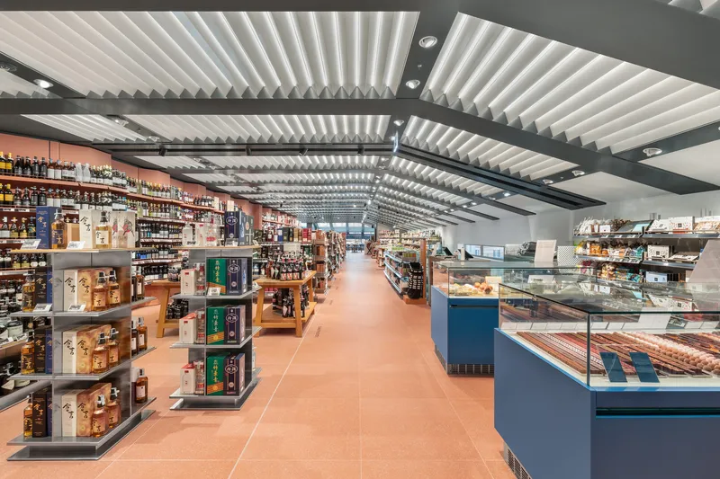 Interior retail space with terracotta tile floor and folded white acoustic ceiling panels above product displays
