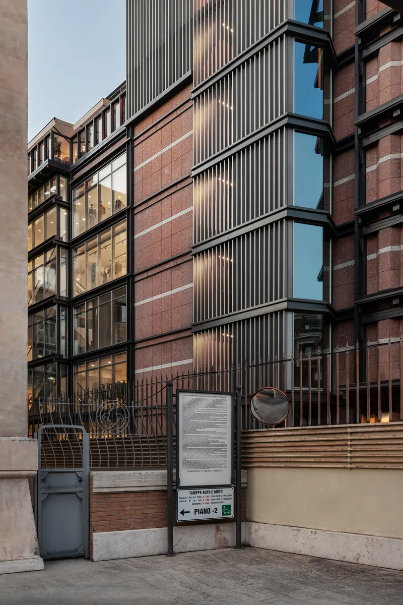 Ground level entrance with horizontal timber slats, metal gate and red brick facade at dusk