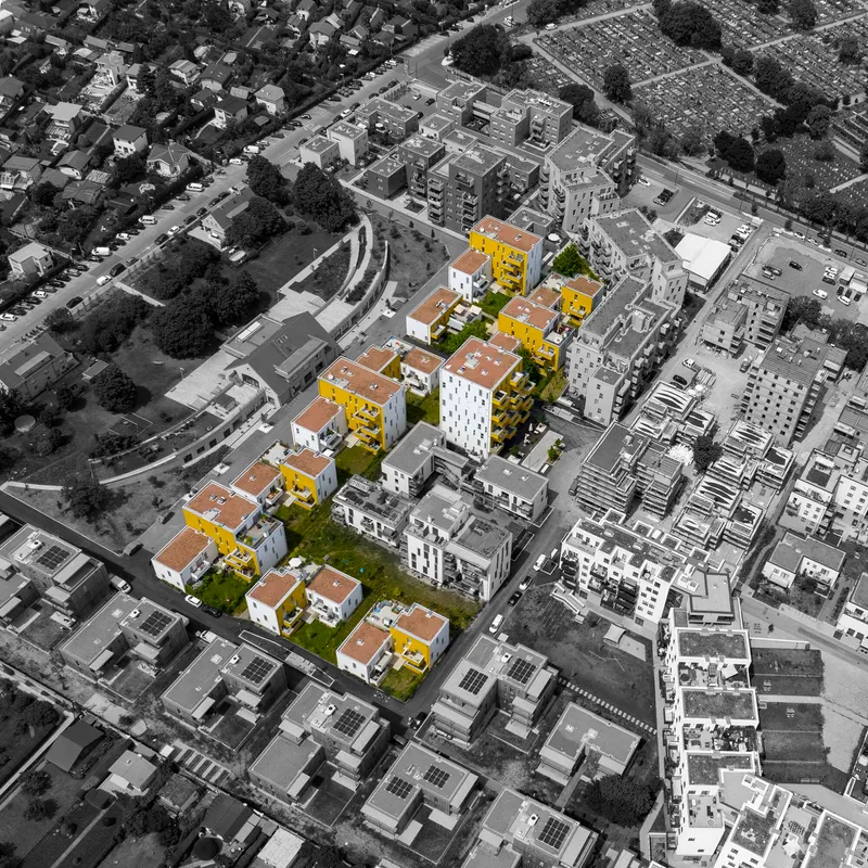 Aerial view of housing blocks with yellow and white facades highlighted in color among surrounding development