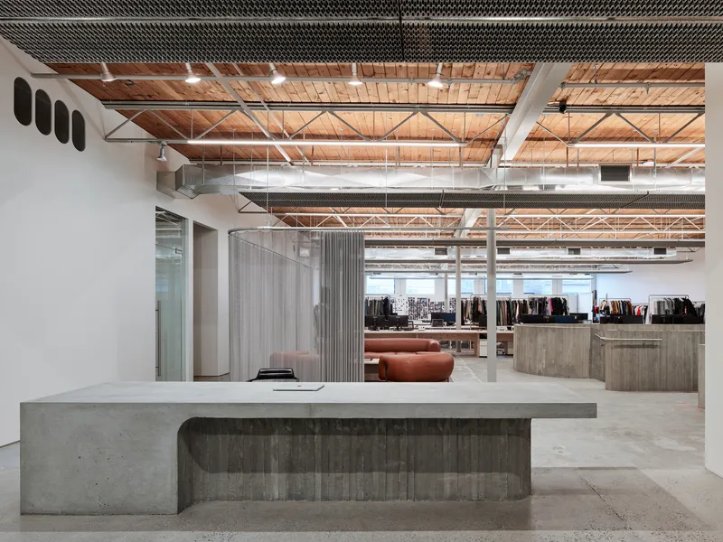 Open plan workspace with timber plank ceiling, exposed trusses, and concrete reception desk