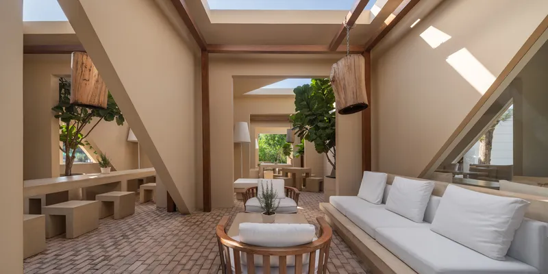 Seating area beneath timber roof beams and rectangular skylights with planters and built-in benches