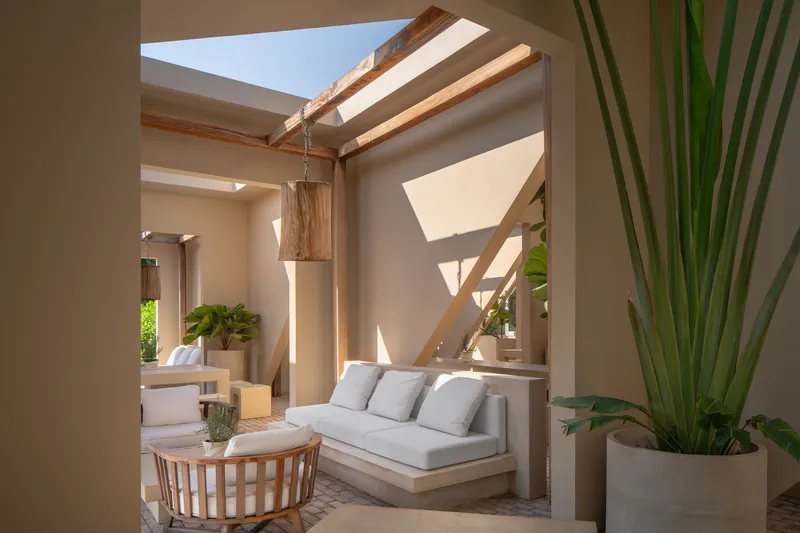 Interior courtyard with timber beam structure, skylights, and geometric shadows on stucco walls