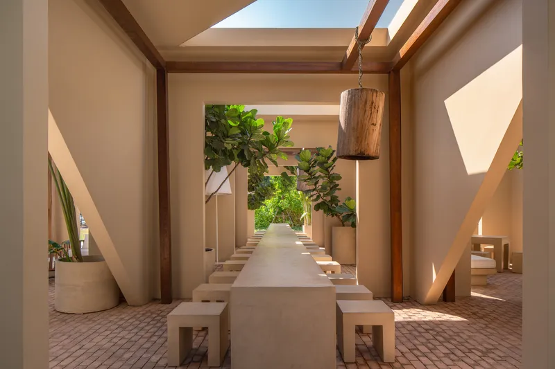 Interior dining space with a long table and benches beneath a skylight framed by timber beams