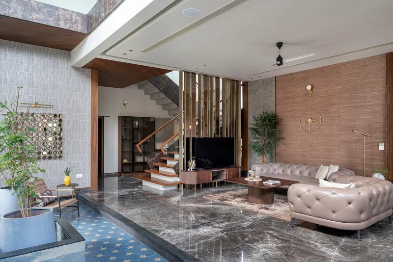 Double-height living room with polished grey stone floor and open staircase beneath skylight