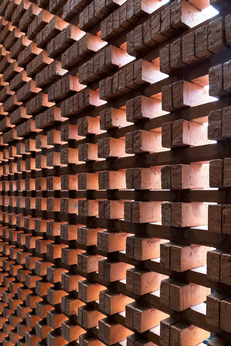 Perforated brick screen wall with staggered bonding pattern creating gaps of light and shadow