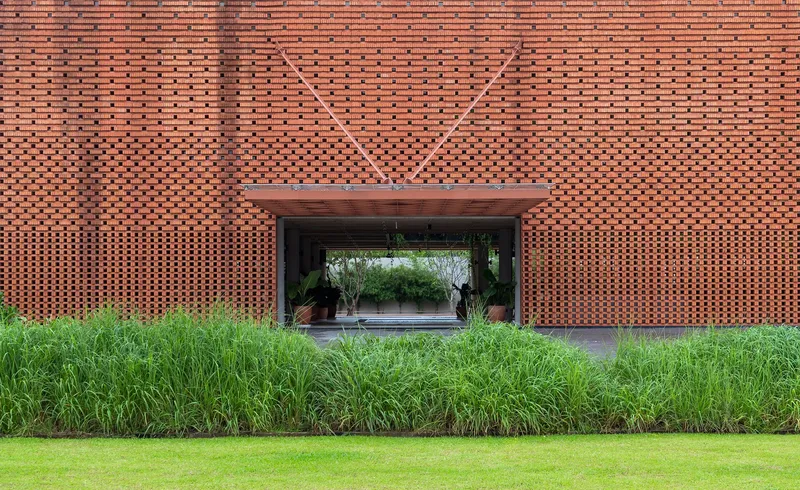 Straight-on view of covered entrance through perforated brick facade with geometric relief pattern