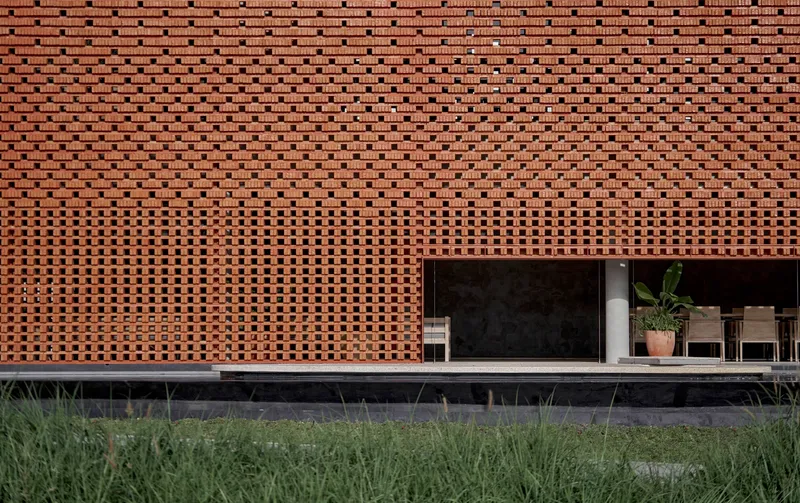 Close-up of perforated brick screen with varying density above recessed glass opening