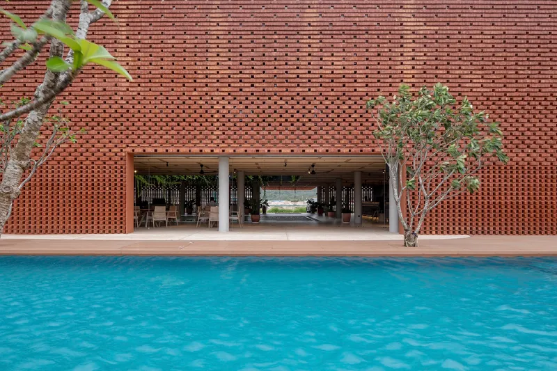 View across swimming pool toward covered pavilion with timber ceiling and potted tree