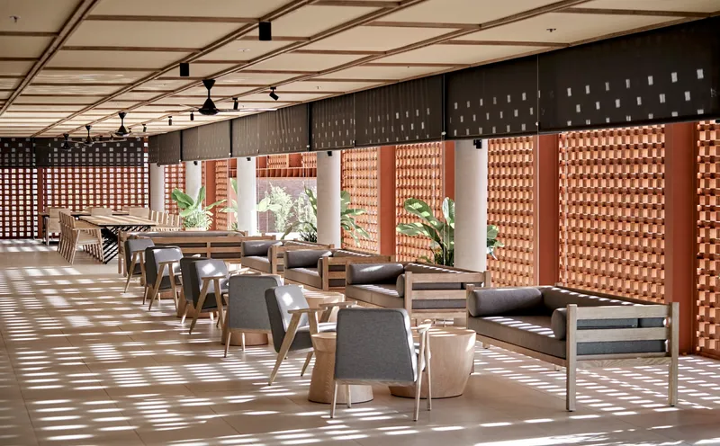 Dining area with lattice brick screens filtering dappled sunlight across timber furniture and pale terrazzo floor