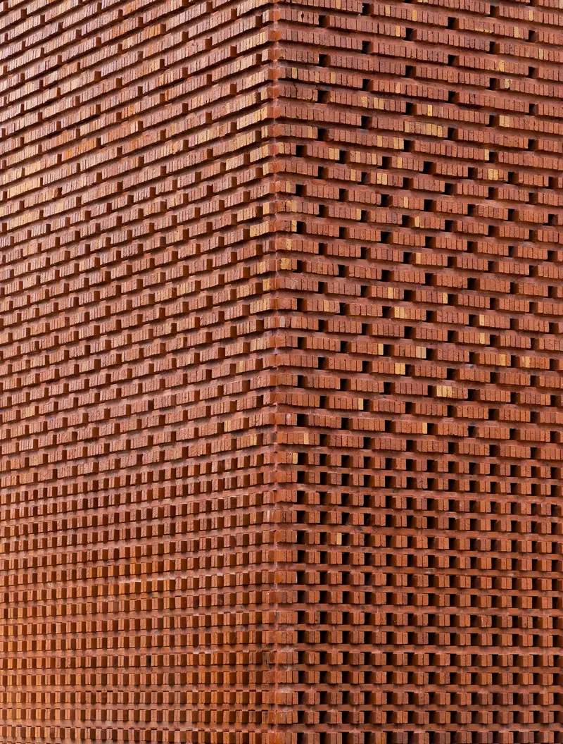 Close-up of the perforated brick screen showing undulating surface and staggered bond pattern