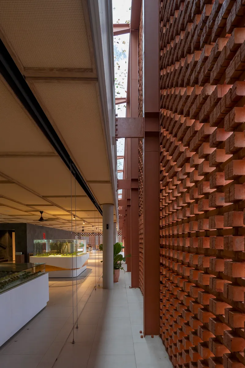 Narrow skylit passage between lattice brick wall and interior dining space with ceiling fans