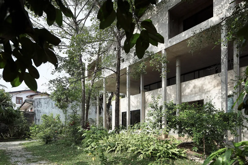 Elevated concrete structure on columns surrounded by mature trees and sloping garden