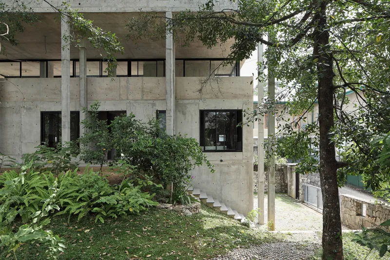 Angled view of the concrete volume with ribbon windows and landscaped hillside garden