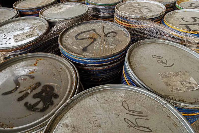Stacked paint can lids with handwritten markings used as facade modules during construction