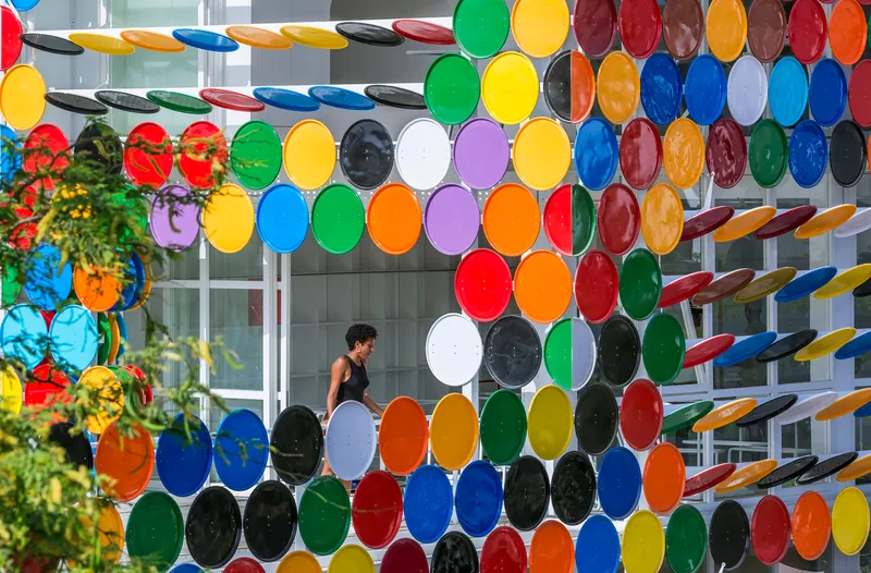 Interior view through the circular disc screen showing a figure walking past planted flowers in coloured pots