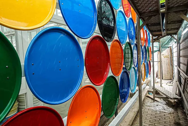 Interior view through circular colored glass panel wall with timber ceiling and construction debris beyond