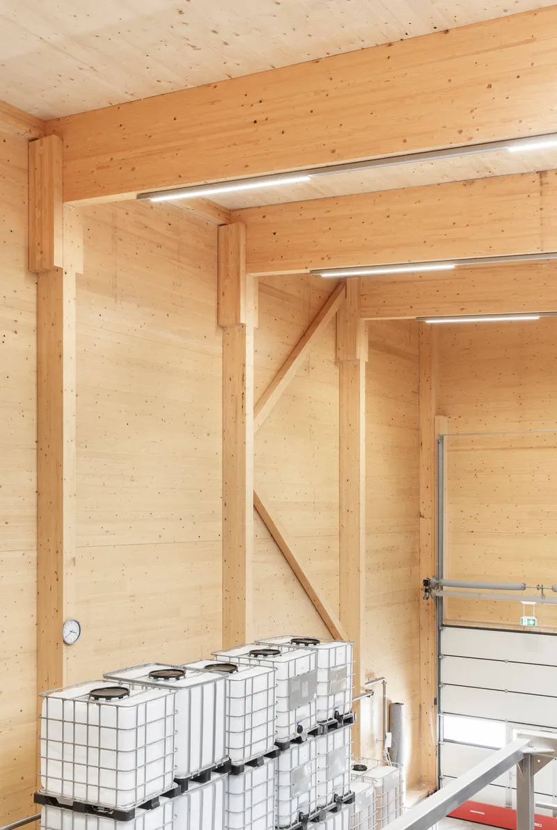 Corner detail of timber post and beam frame with white storage containers at floor level