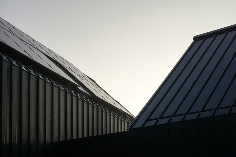 Upward view of two gabled rooflines meeting in a V against an overcast sky