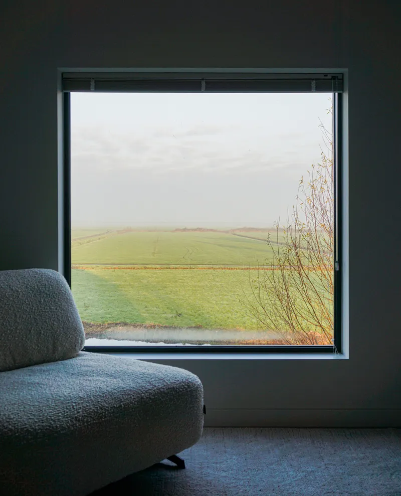 Square window seat overlooking green farmland and grasses in misty weather