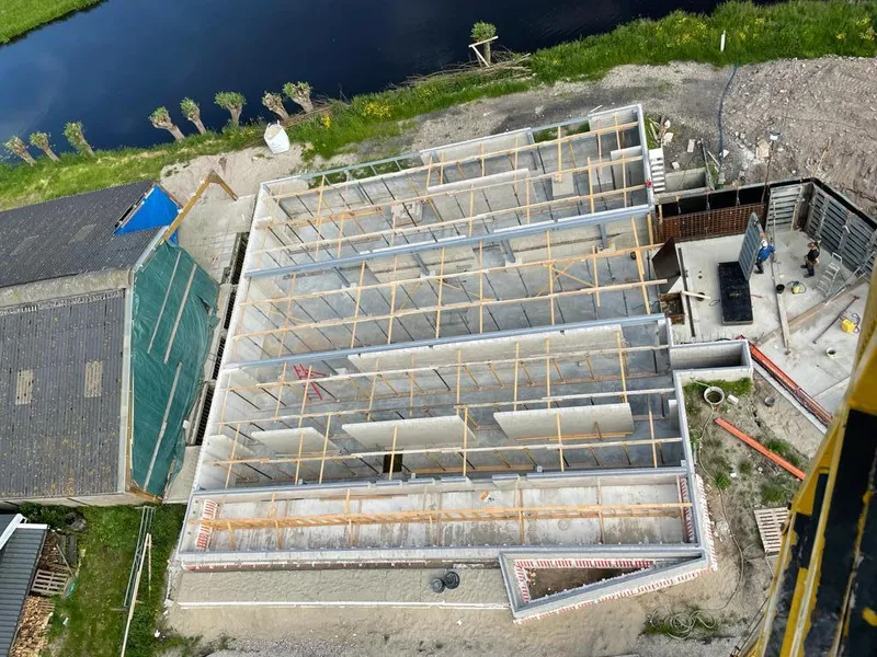 Aerial view of timber roof framing during construction beside a canal