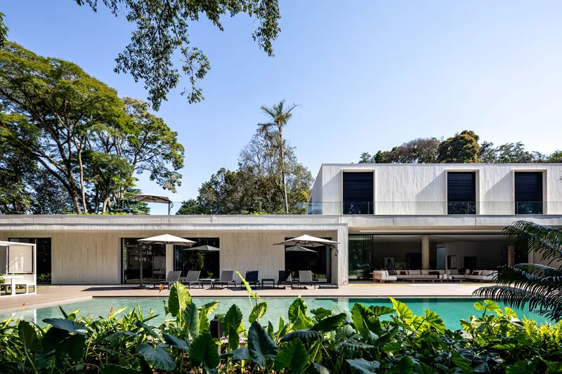 Rear facade with covered terrace overlooking a swimming pool framed by tropical planting