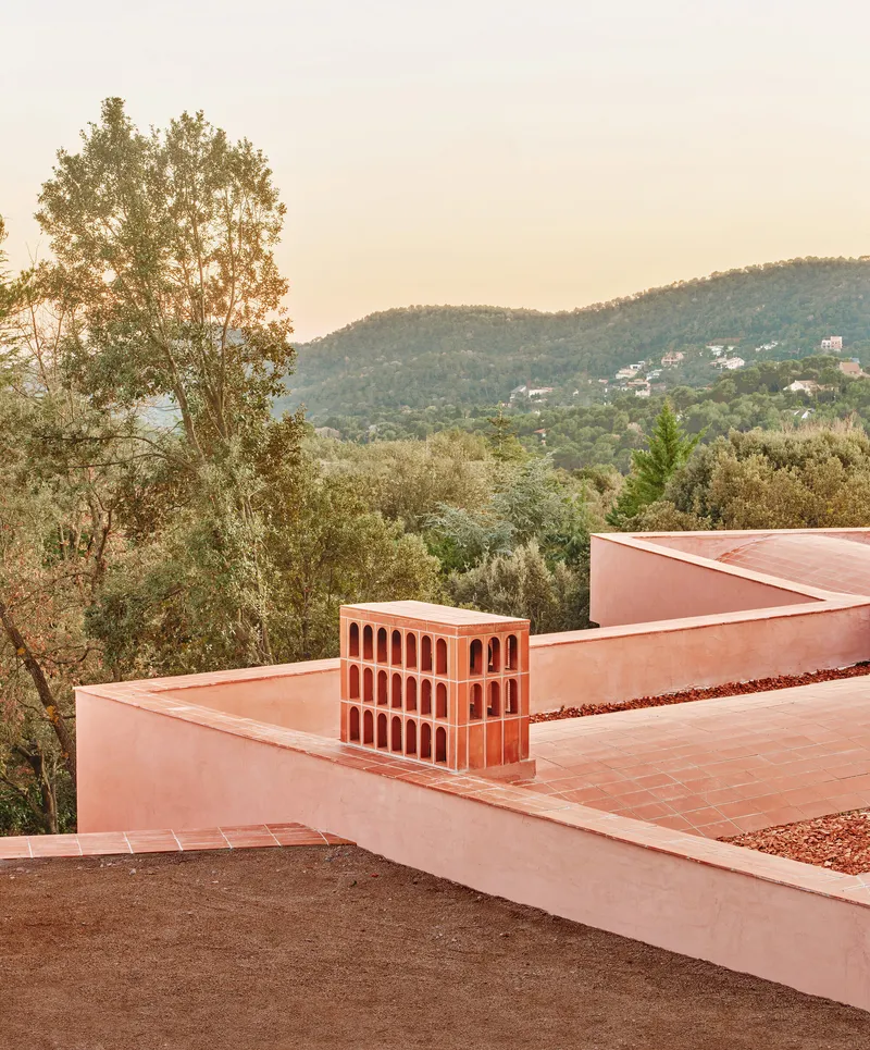 Terraced roof with terracotta chimney structure overlooking forested hillside at dusk