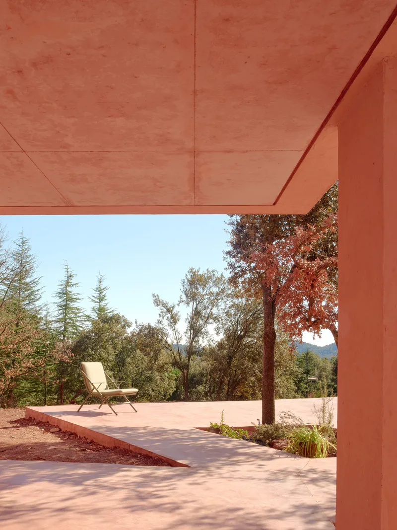 View through the timber soffit frame toward a terrace and distant tree line