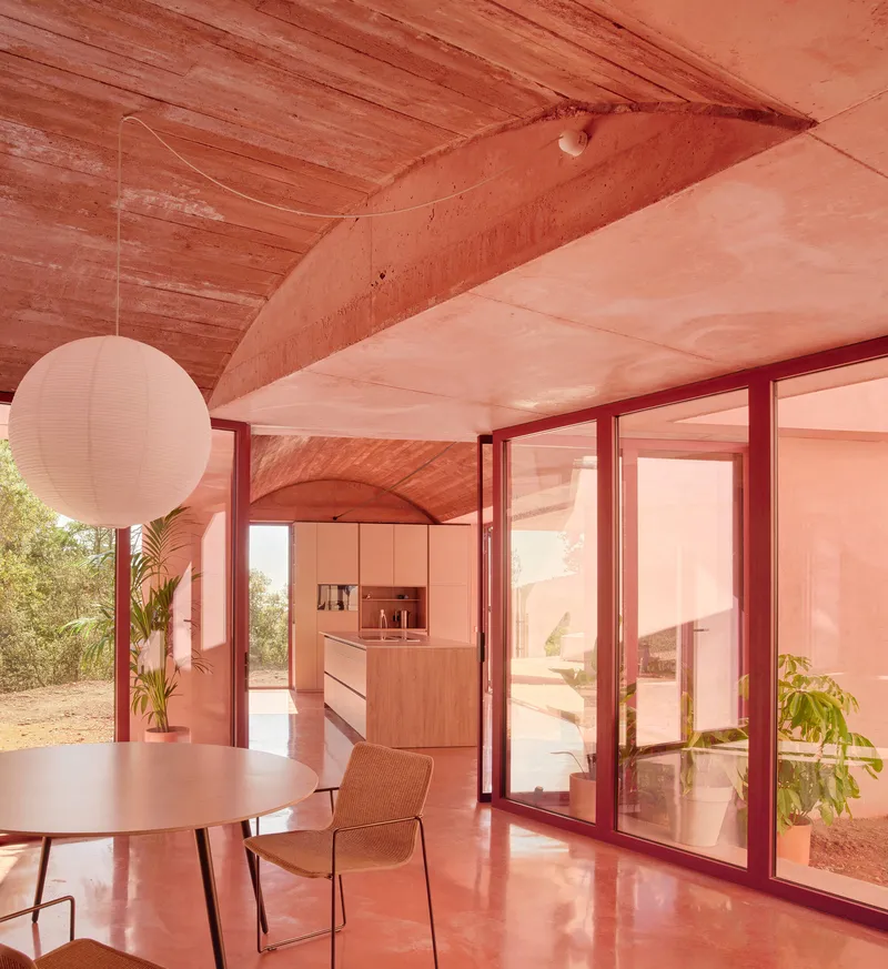 Interior dining space with vaulted timber ceiling and glazed doors opening to courtyard
