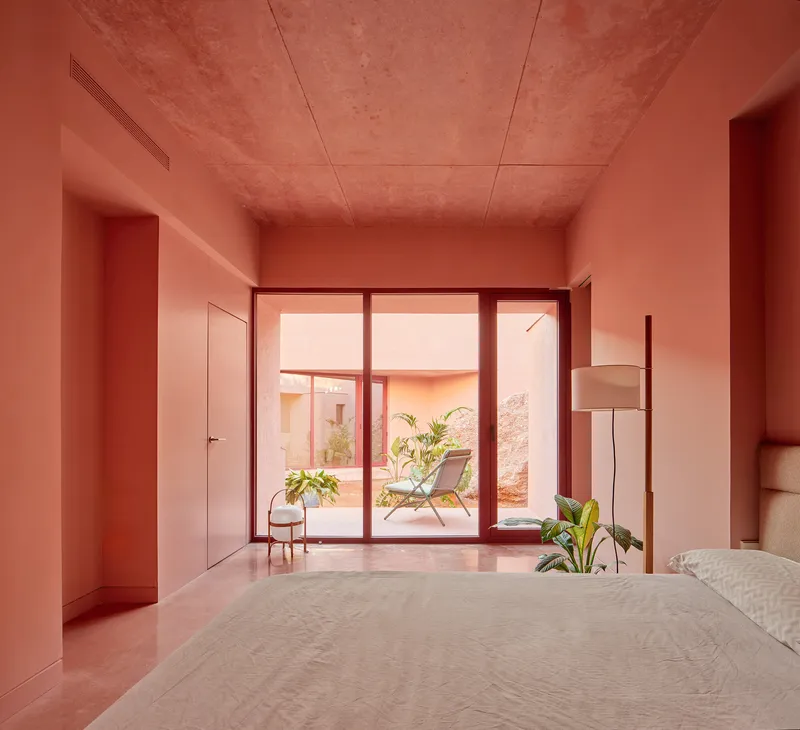 Bedroom with glazed doors opening to courtyard and lounge chair visible beyond the threshold