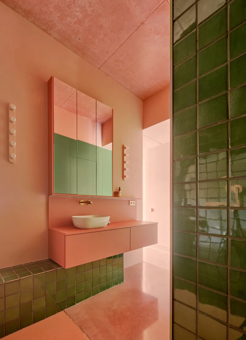 Bathroom with pink floating vanity, green glazed tile shower wall and mirrored cabinets