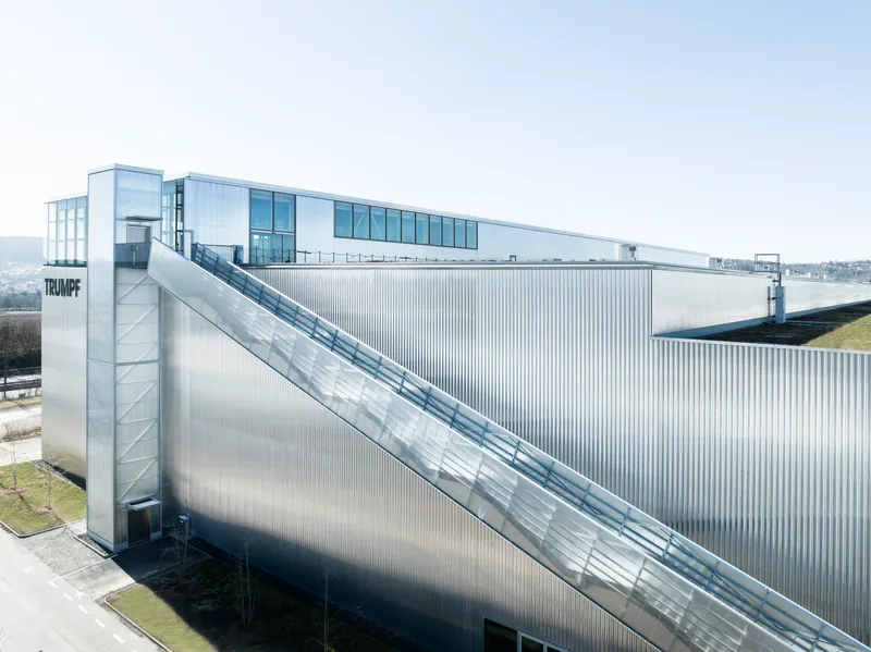 Corrugated metal facade with diagonal exterior staircase leading to a glazed upper volume