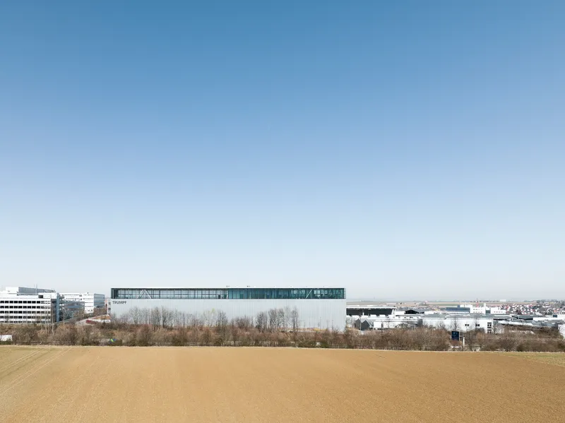 Distant view of the elevated transparent volume above industrial roofscape and bare winter trees