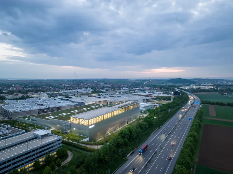 Aerial view of the illuminated industrial building along the highway at dusk