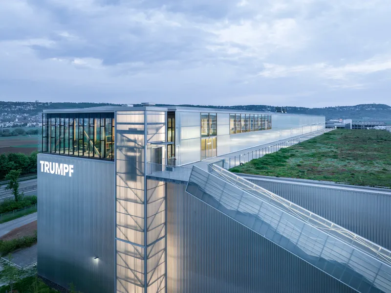 Tower element with vertical glass stairwell and corrugated metal cladding at twilight
