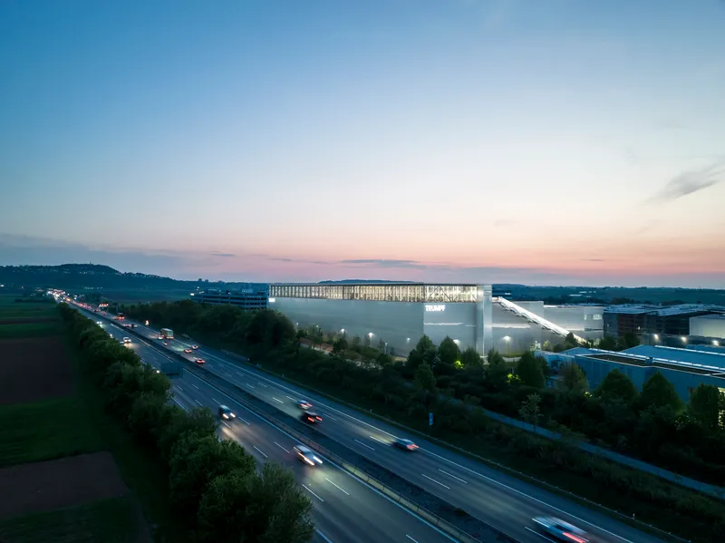 Long exposure view of the illuminated facility beside the highway with passing traffic