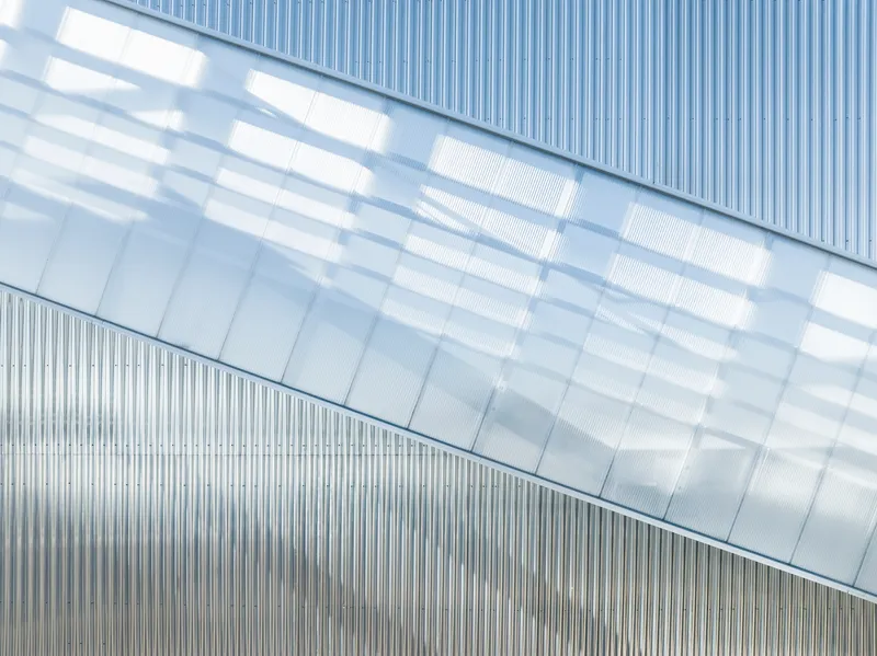 Close-up of the angled glazed bridge against vertically ribbed metal cladding