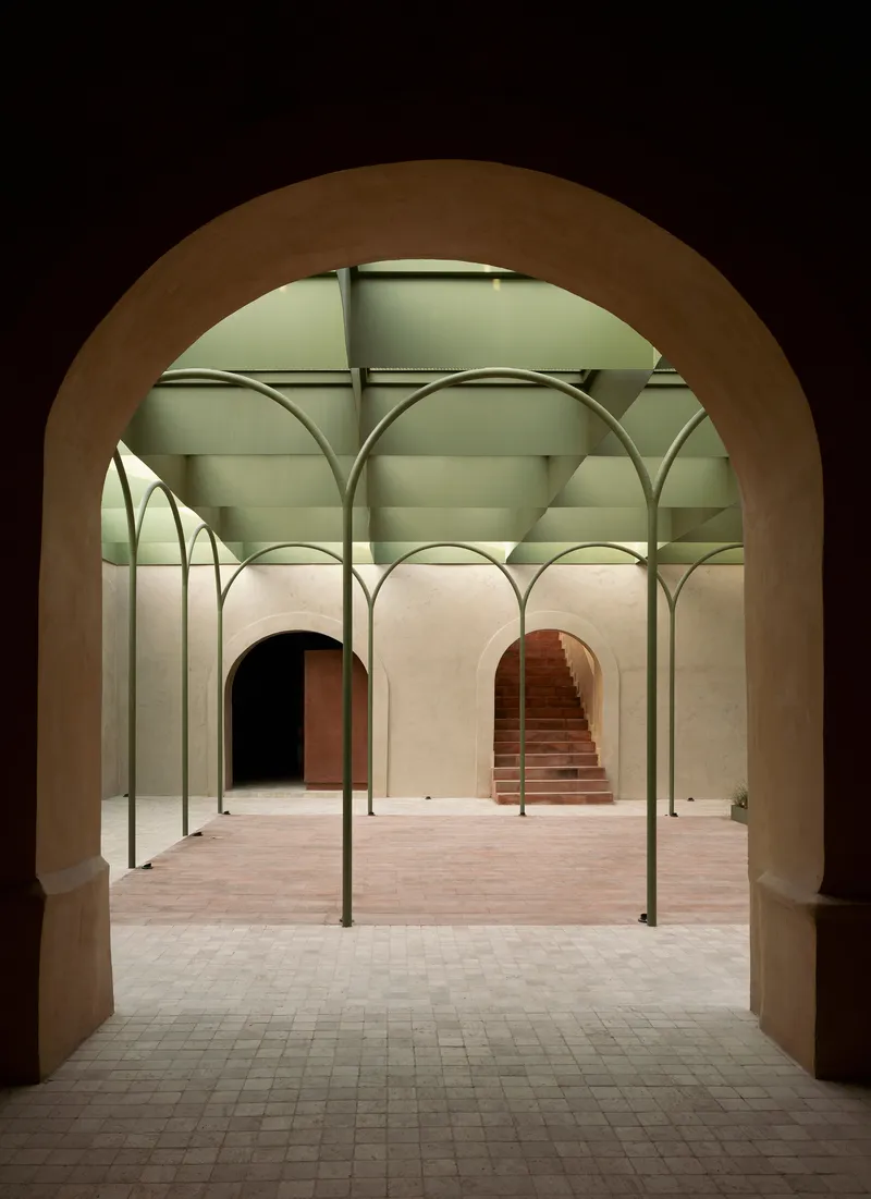 View through a thick arched opening into the colonnade courtyard at dusk