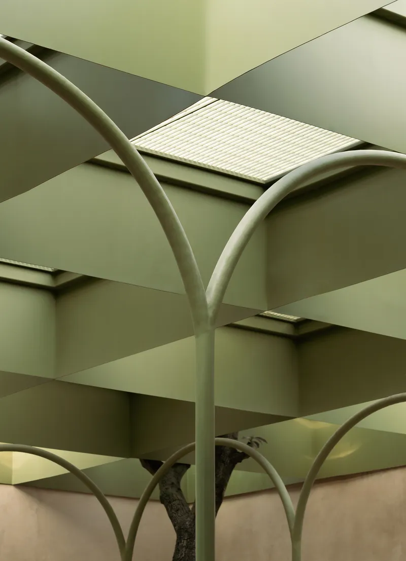 Close-up of the green steel arches branching beneath the coffered ceiling with translucent skylight panels