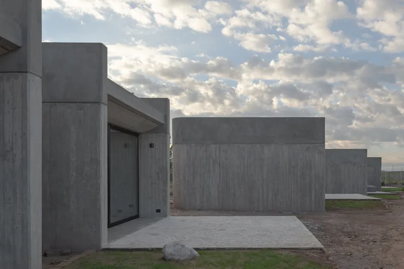 Boardformed concrete courtyard with stepped volumes under a cloudy afternoon sky