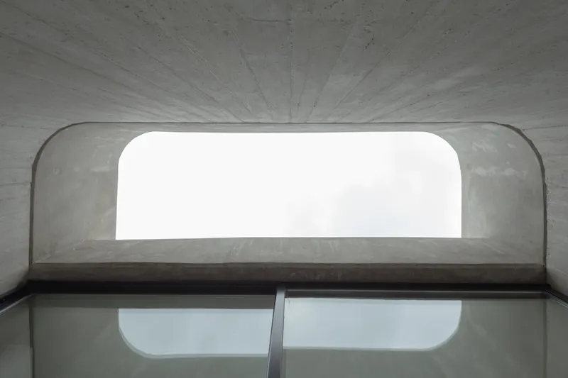 Interior view up through curved concrete vault with rounded window opening overhead