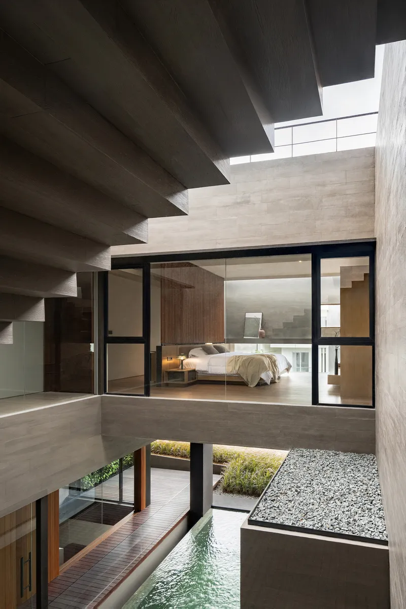 Interior courtyard showing cantilevered bedroom, exposed concrete stairs and pool with gravel bed
