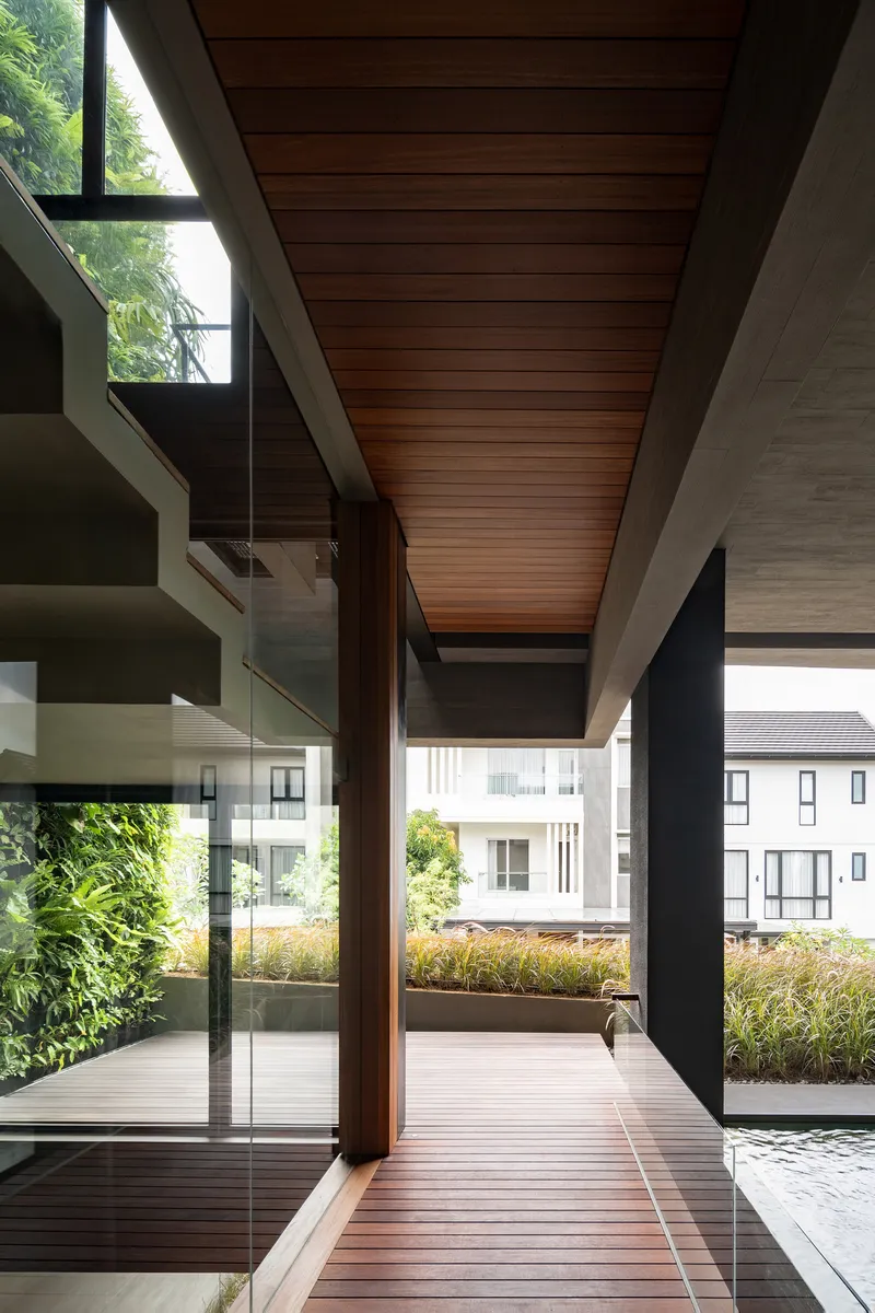 Covered walkway with timber decking and slatted wood ceiling looking toward neighboring houses