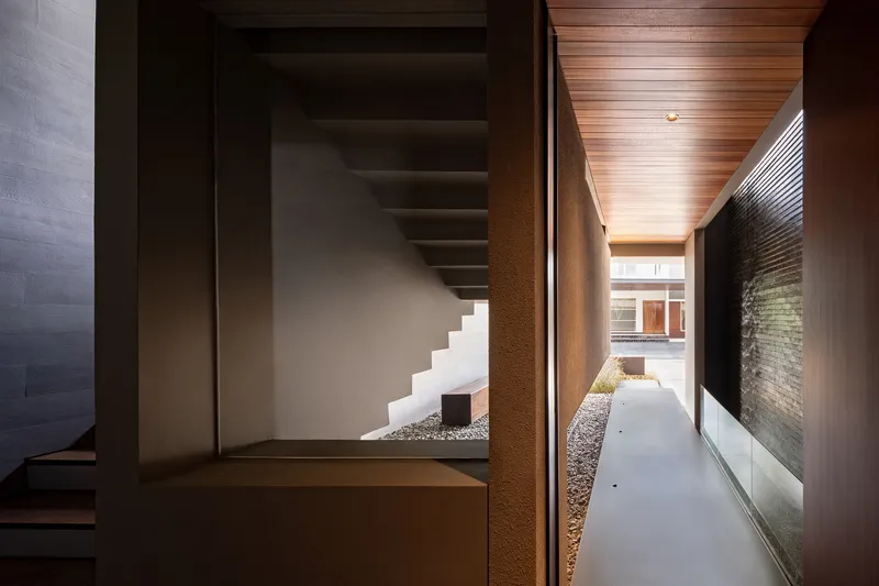 Interior corridor with timber ceiling panels and glimpse of staircase beyond a glazed opening