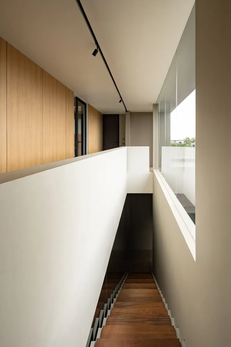 Upper-level hallway with timber-lined walls and narrow staircase descending beneath a white parapet