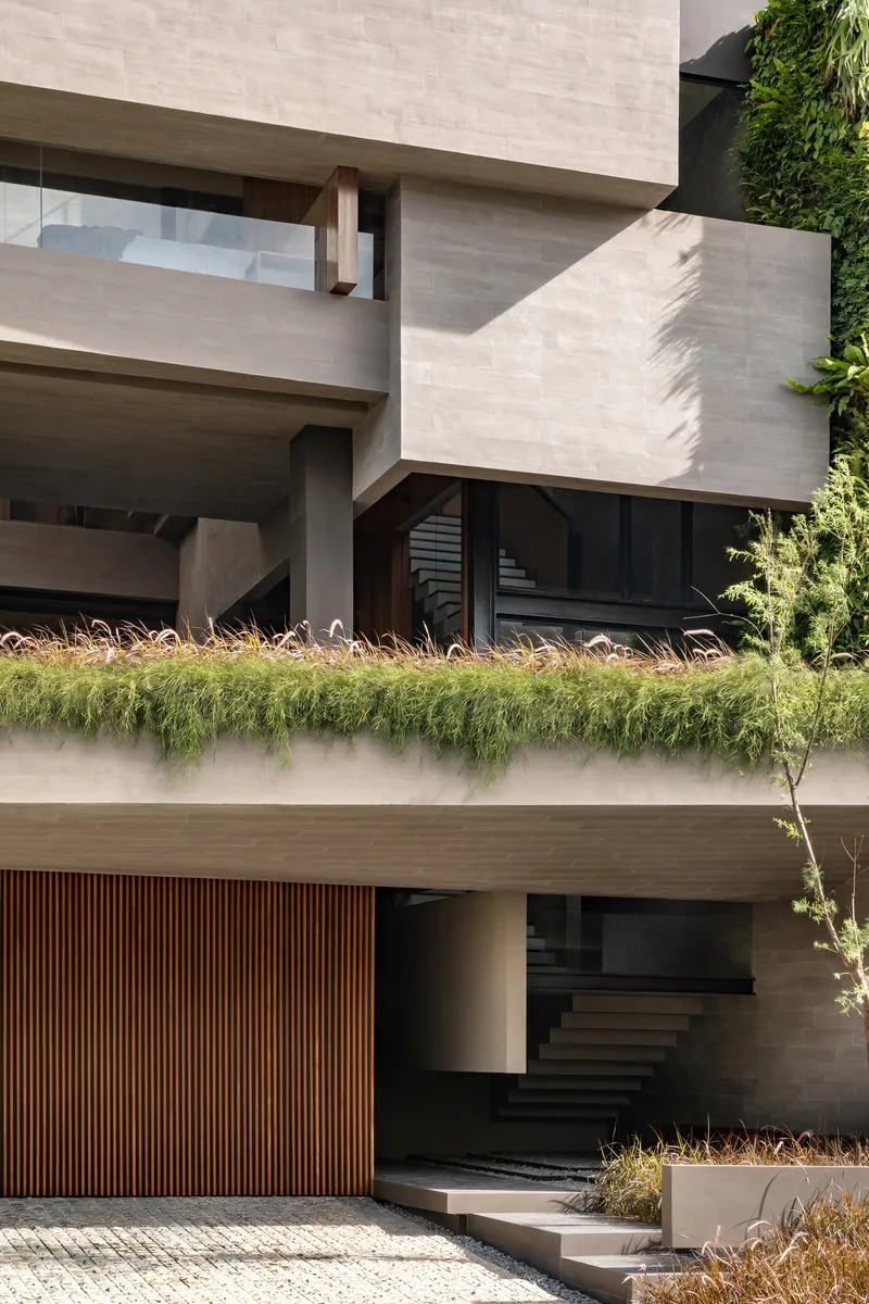 Layered concrete balconies with planted edge, timber screening and entry stair in afternoon sunlight