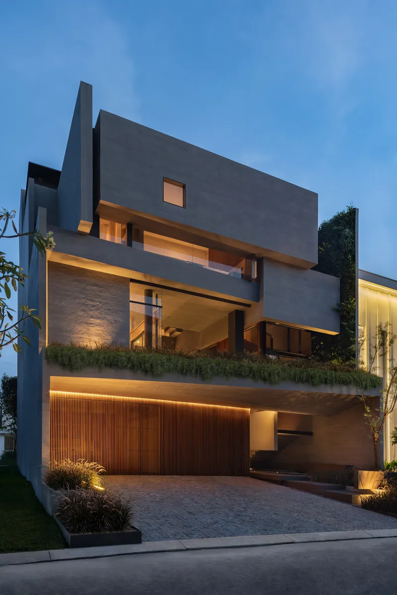 Street facade at dusk showing stacked volumes with planted terraces and timber slatted garage screen